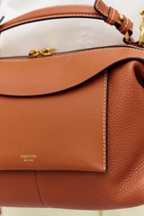 Profile view of model wearing the Oroton Mica Bowler in Brandy and Premium pebble grain leather for Women .