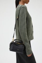 Profile view of model wearing the Oroton Mica Mini Bowler in Black and Premium pebble leather for Women .