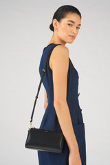 Profile view of model wearing the Oroton Harvey Baguette Crossbody in Black and Smooth leather for Women .