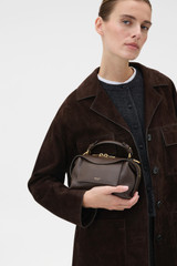 Profile view of model wearing the Oroton Mica Mini Bowler in Dark Chocolate and Premium pebble leather for Women .