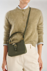 Profile view of model wearing the Oroton Dylan Mini Baguette Crossbody in CACTUS and Premium pebble leather for Women .