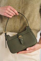 Profile view of model wearing the Oroton Dylan Mini Baguette Crossbody in CACTUS and Premium pebble leather for Women .