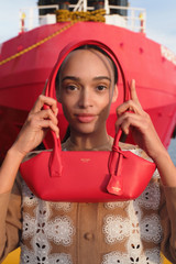 Profile view of model wearing the Oroton Breeze Baguette in Market Red and Premium smooth leather for Women .