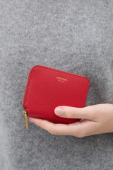 Profile view of model wearing the Oroton Iris Small Zip Wallet in Dark Ruby and Premium pebble leather  for Women .