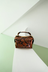 Profile view of model wearing the Oroton Mica Mini Bowler in Copper Snake and Premium textured leather for Women .