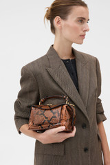 Profile view of model wearing the Oroton Mica Mini Bowler in Copper Snake and Premium textured leather for Women .