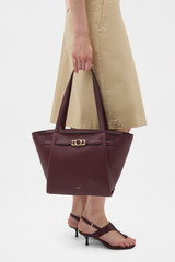 Profile view of model wearing the Oroton Juliette Medium Tote in Burgundy and Premium pebble leather for Women .
