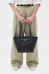 Profile view of model wearing the Oroton Juliette Medium Tote in Black and Premium pebble leather for Women .