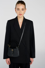 Profile view of model wearing the Oroton Dylan Mini Baguette Crossbody in Black and Premium pebble leather for Women .