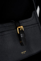 Profile view of model wearing the Oroton Dylan Mini Baguette Crossbody in Black and Premium pebble leather for Women .