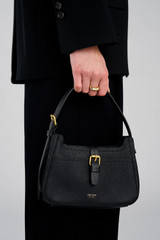Profile view of model wearing the Oroton Dylan Mini Baguette Crossbody in Black and Premium pebble leather for Women .