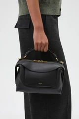 Profile view of model wearing the Oroton Mica Bowler in Black and Premium pebble grain leather for Women .