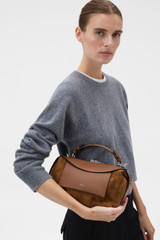 Profile view of model wearing the Oroton Mica Mini Bowler in Teak and Premium suede leather for Women .