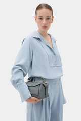 Profile view of model wearing the Oroton Mica Texture Mini Bowler in Soot and Premium embossed ostrich leather for Women .