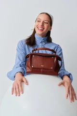 Profile view of model wearing the Oroton Mica Burnished Leather Bowler in Dark Chestnut and Smooth, vegetable-tanned leather for Women .