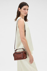 Profile view of model wearing the Oroton Mica Burnished Leather Mini Bowler in Dark Chestnut and Smooth, vegetable-tanned leather for Women .