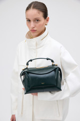 Profile view of model wearing the Oroton Mica Crackle Bowler in Shade Green and Premium crackle leather for Women .
