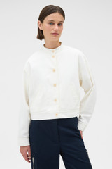 Profile view of model wearing the Oroton Curved Sleeve Jacket in Antique White and 100% cotton fabric for Women .