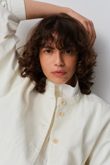 Profile view of model wearing the Oroton Curved Sleeve Jacket in Antique White and 100% cotton fabric for Women .