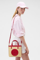 Profile view of model wearing the Oroton Polly Straw Small Tote in Natural/Dark Ruby and Woven straw material for Women .