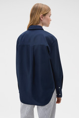 Profile view of model wearing the Oroton Oxford Shirt in North Sea and 100% cotton fabric for Women .