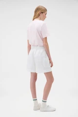 Profile view of model wearing the Oroton Flat Front Carpenter Short in Antique White and 100% cotton fabric for Women .